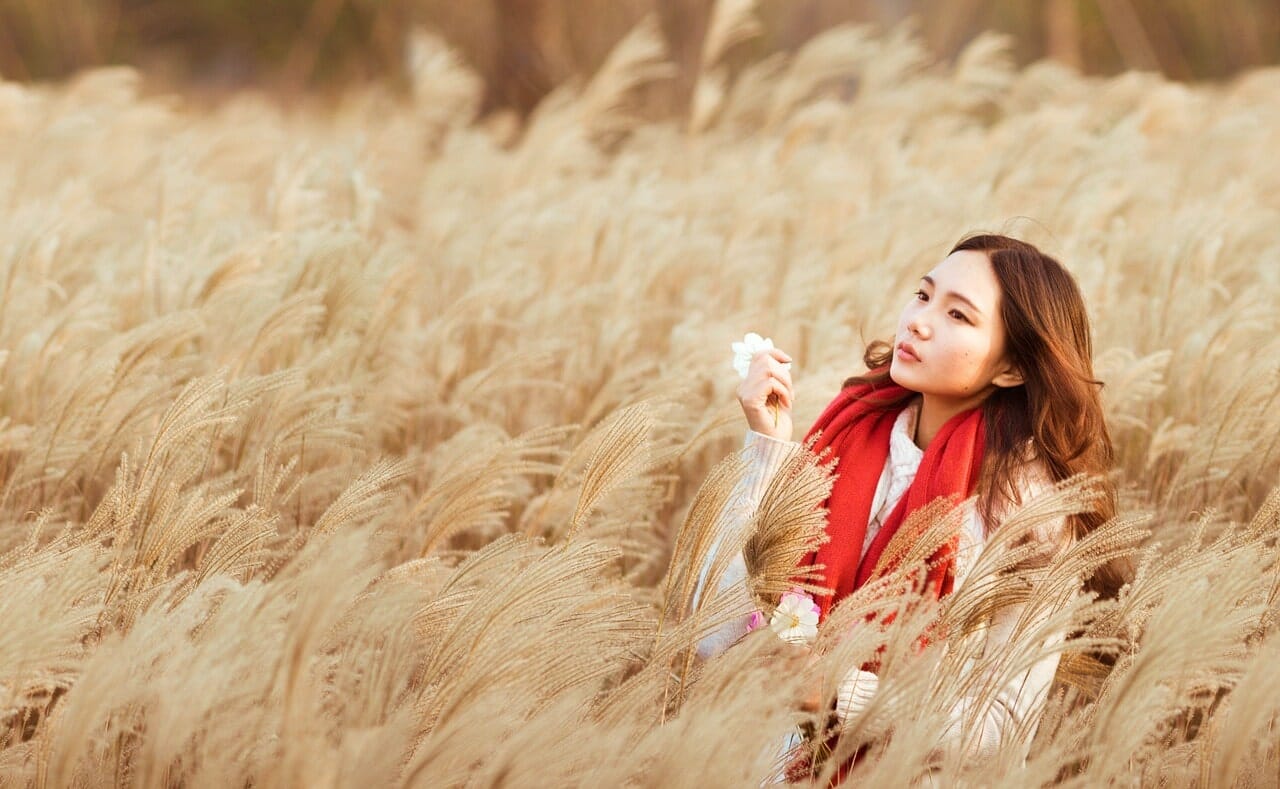 An Asian woman in a field of reeds.