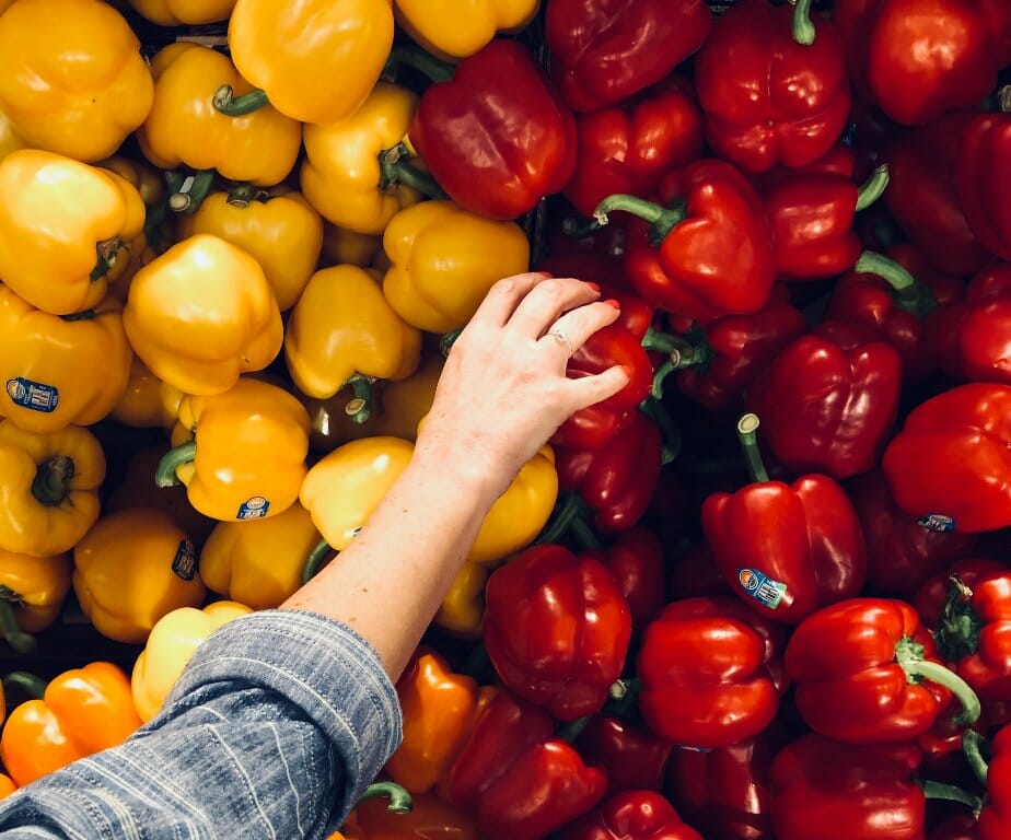 A woman's hand picking a red capsicum.
