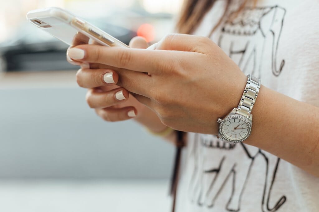 A woman with white painted nails holding her phone.