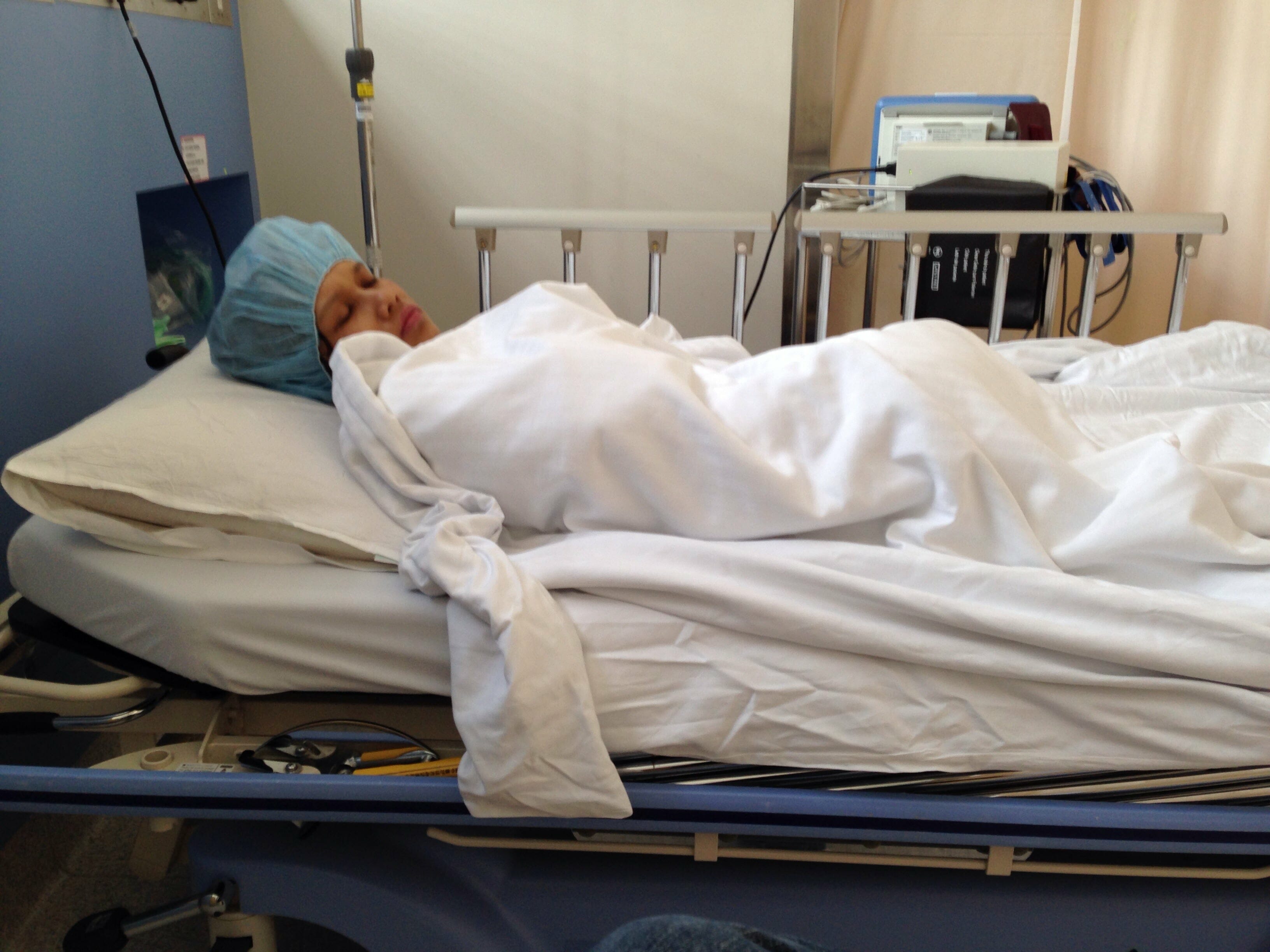 Author lying on a hospital bed wrapped in a blanket.