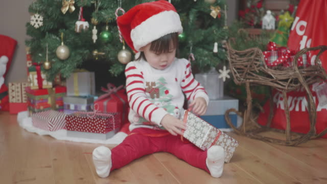Hand Hold Shoot Toddler Baby Girl Open Gift Box In Front Of Christmas Tree