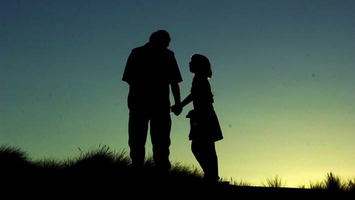 Daughter Pleading With Her Father While Taking His Hand Silhouette Against A Sunset
