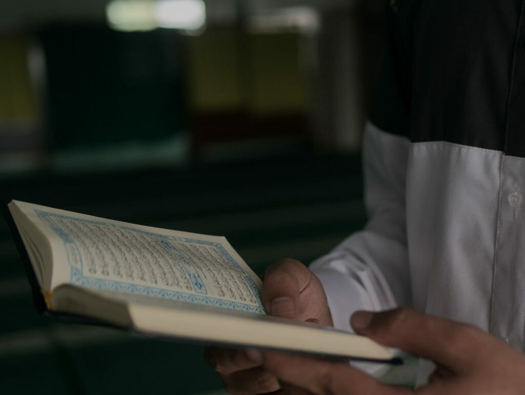 Closeup Of A Person Holding The Quran Open While Reciting It