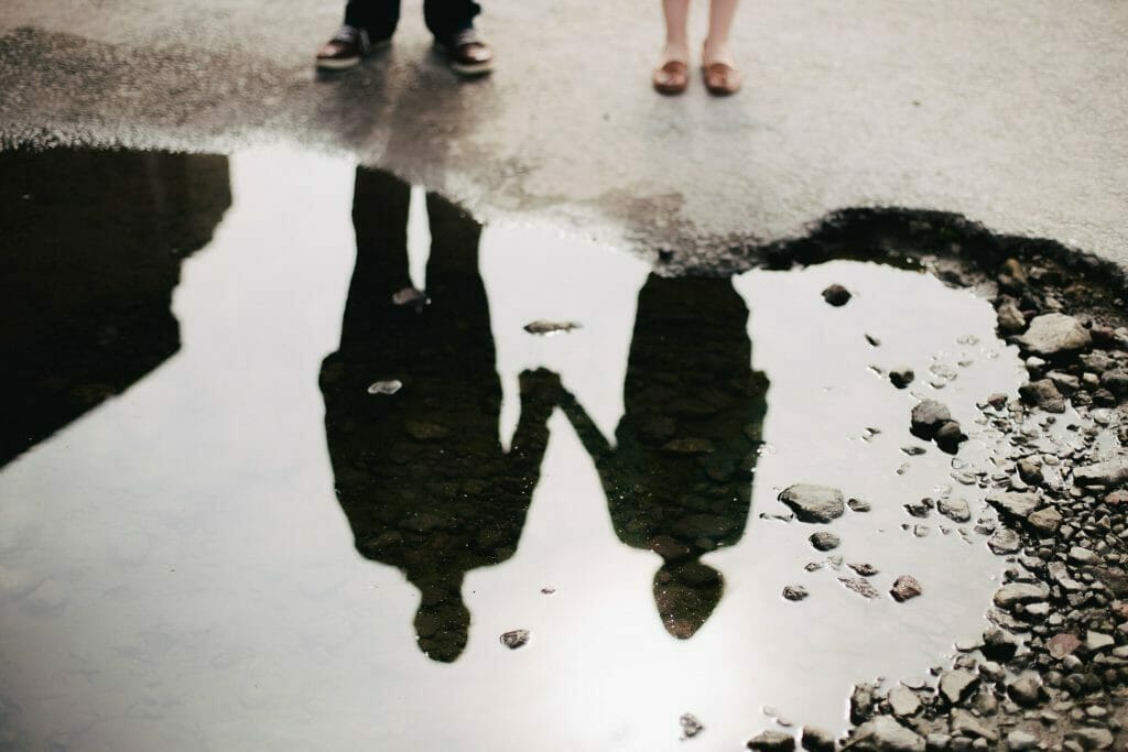 Reflection In The Water Of A Couple Holding Hands