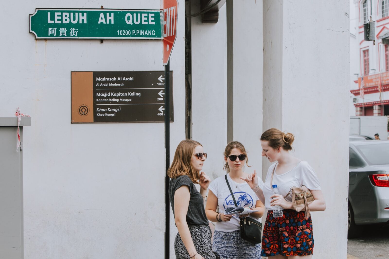 Three European women standing under a street sign in Pulau Pinang