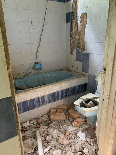 A bathroom with part of the wall collapsed in.