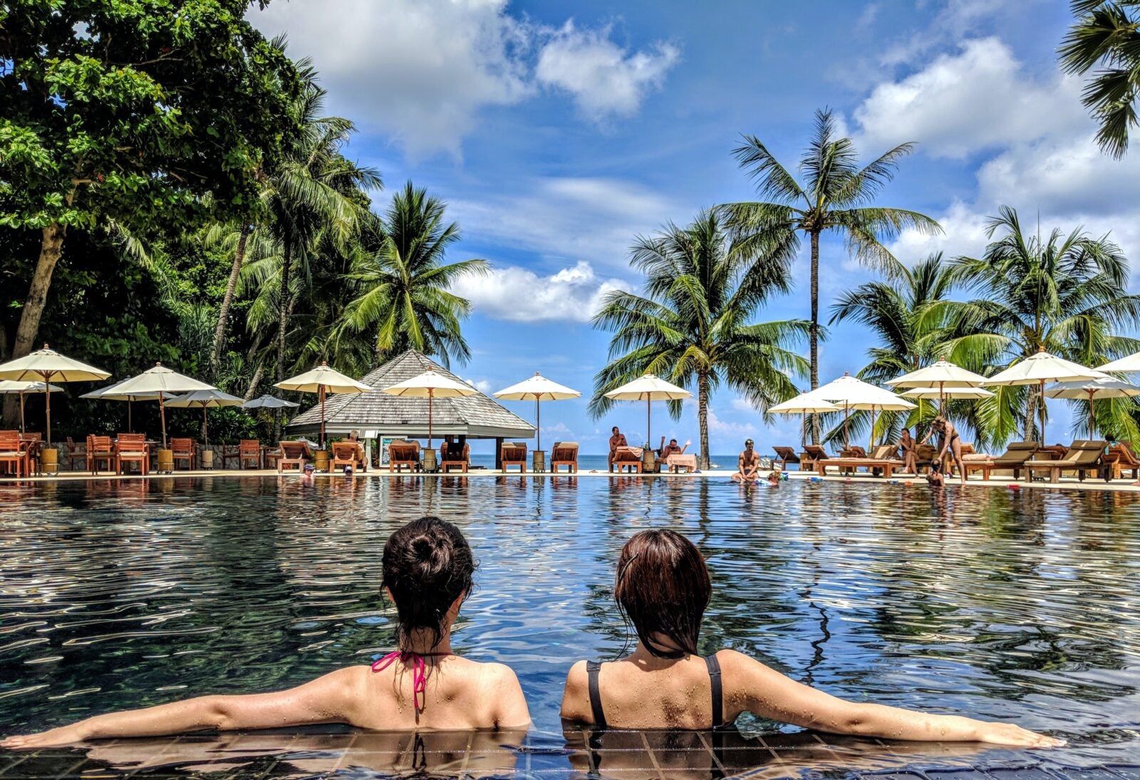 Two women lounging by the side of the pool
