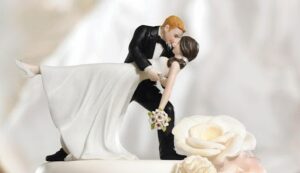 A Married Couple Kissing On Top Of A Wedding Cake