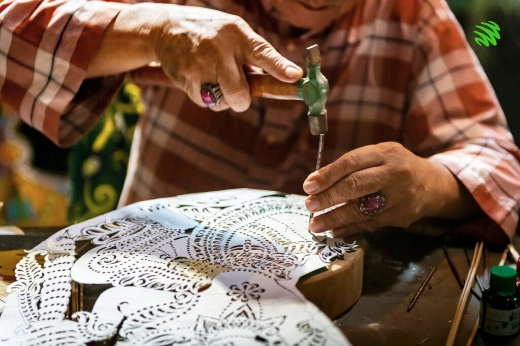 A Practitioner Of Wayang Kulit Working On An Intricate Design Of His Puppet