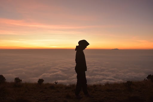 Muslim Girl Above The Clouds Silhouetted Against The Sunrise At Dawn.