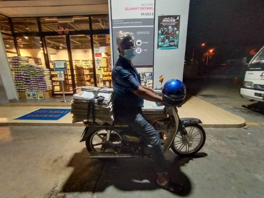 Mr. Shaik Nainar, Sitting Astride His Motorcycle With His Newspaper Delivery Stack At 6Am In The Morning, Outside A Petrol Station In Usj 2, Subang Jaya.