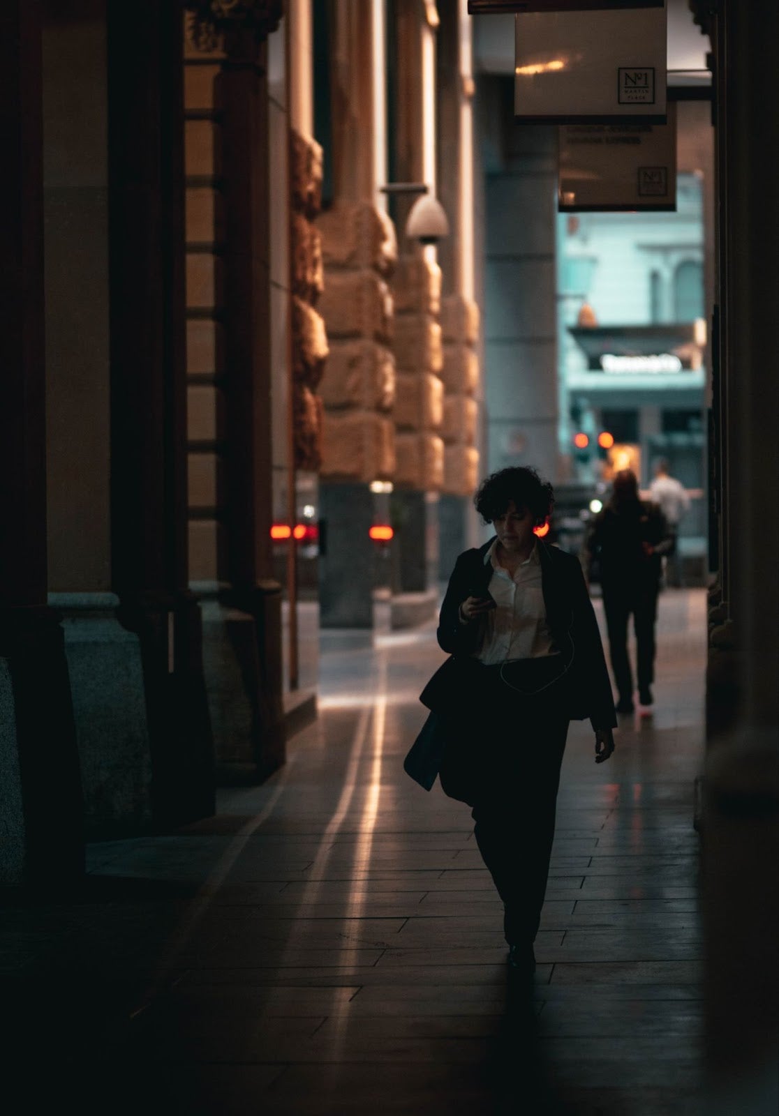 A Woman Walking Down A Dark Alleyway, Unaware She Is Being Stalked By Men.