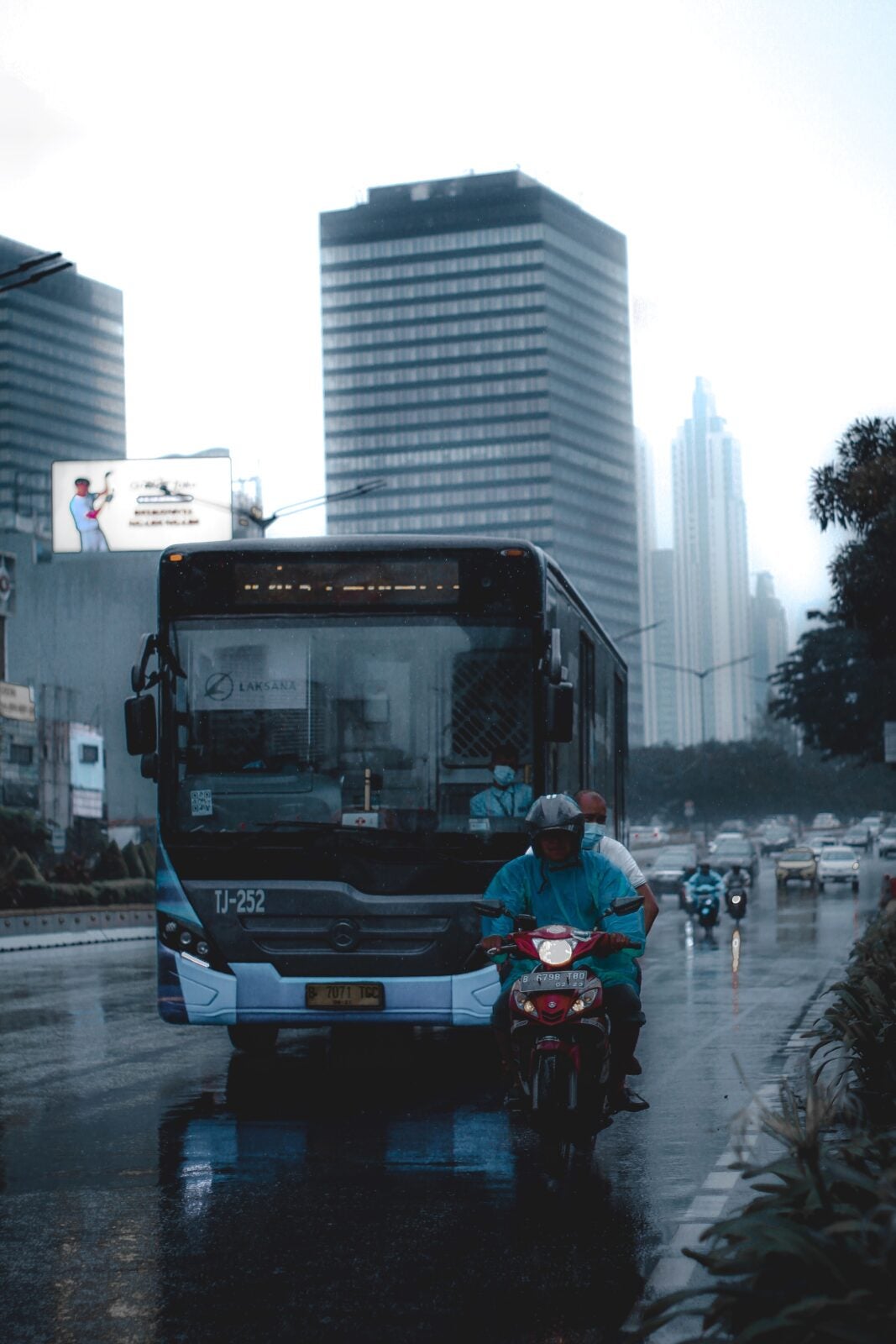 motorcycle next to bus on rainy road