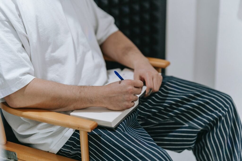 Man Writing In Notebook While Wearing Pajamas