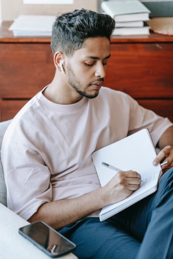 Man Writing On Notebook