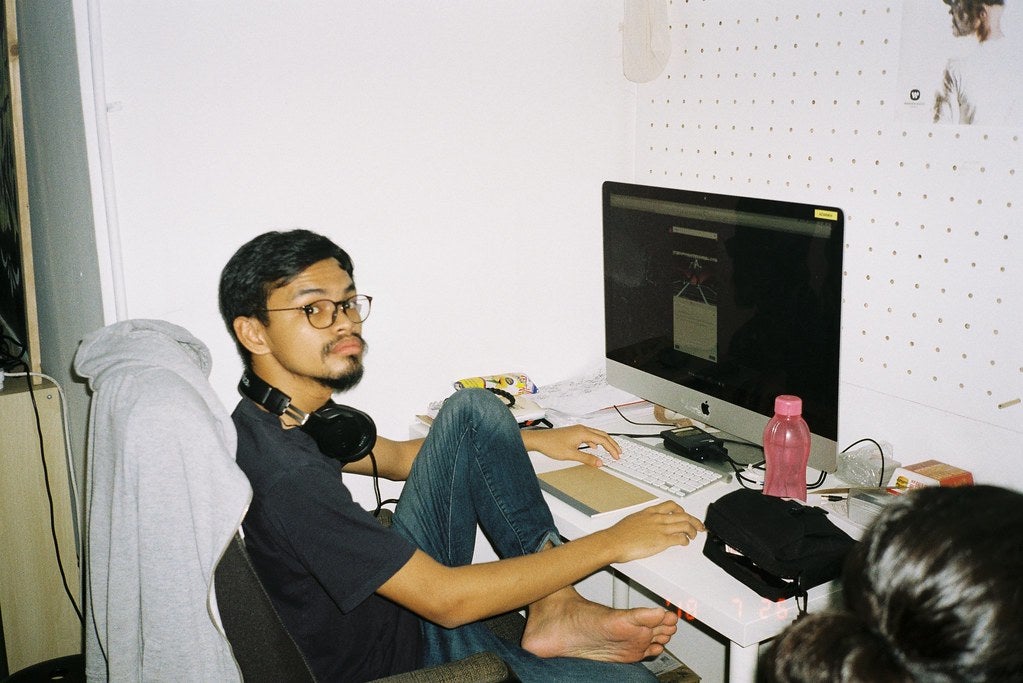 Azarikh, a 3D graphic designer sitting at his workstation, in front of a Mac Computer.