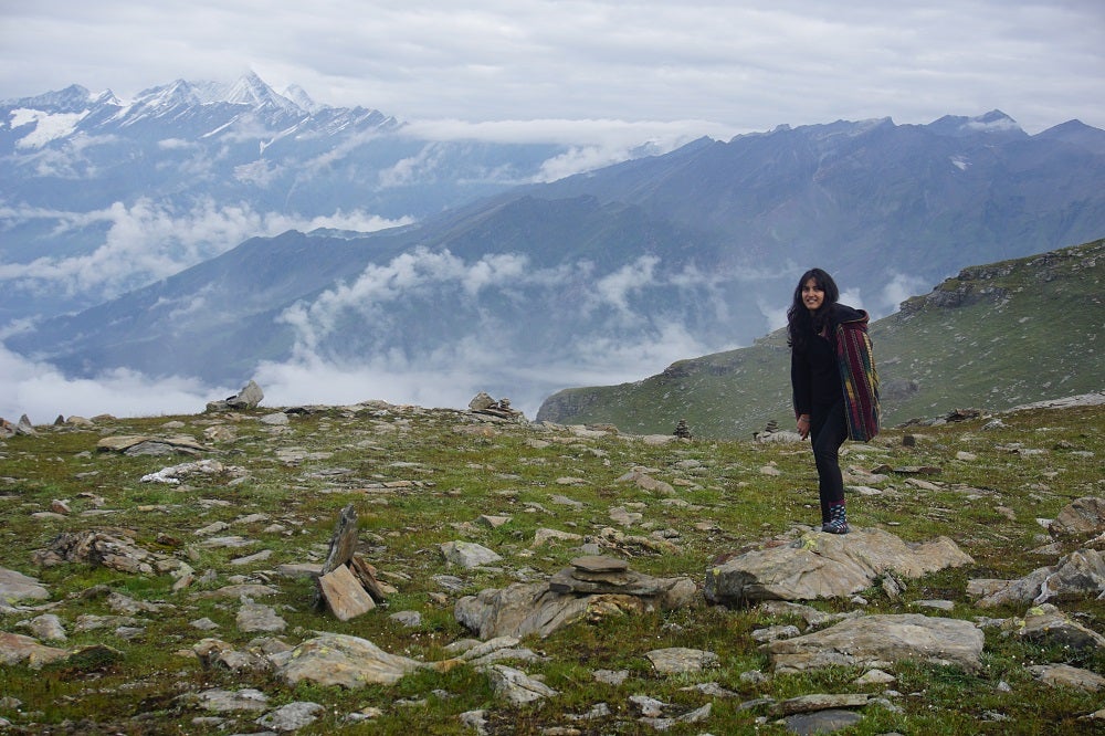 Pashmina standing on a rock at a field. Behind her are mountains and bright skies.