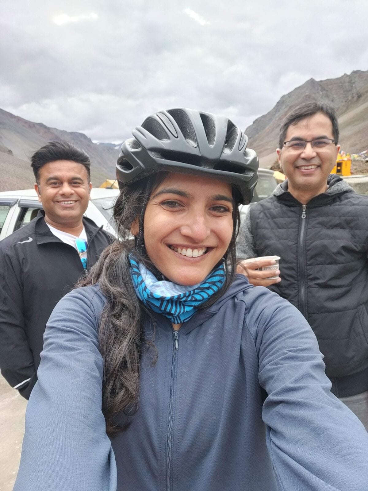 Pashmina wearing her cycling helmet, posing between two men.