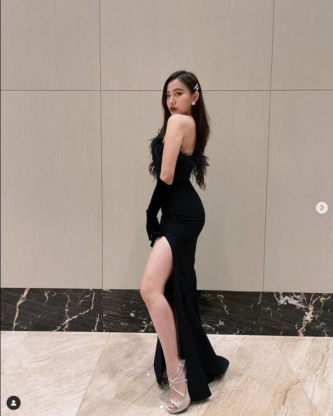 Serene Claire in a long black dress with a slit on one side.