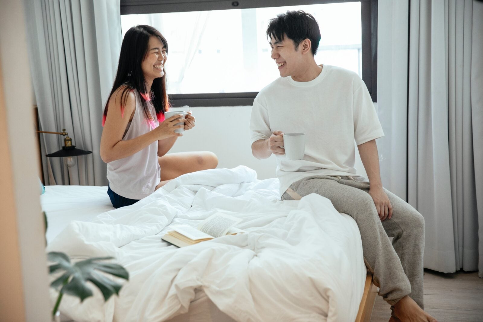A couple sitting in bed and laughing together.