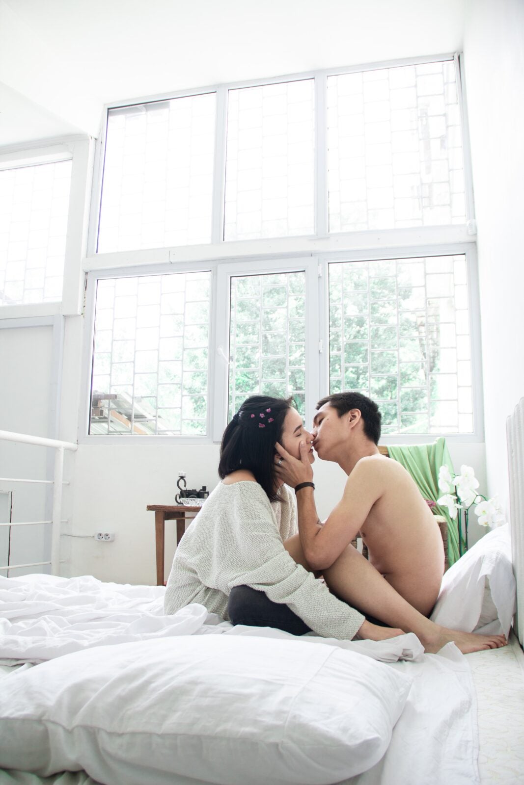 An Asian couple kissing in bed.