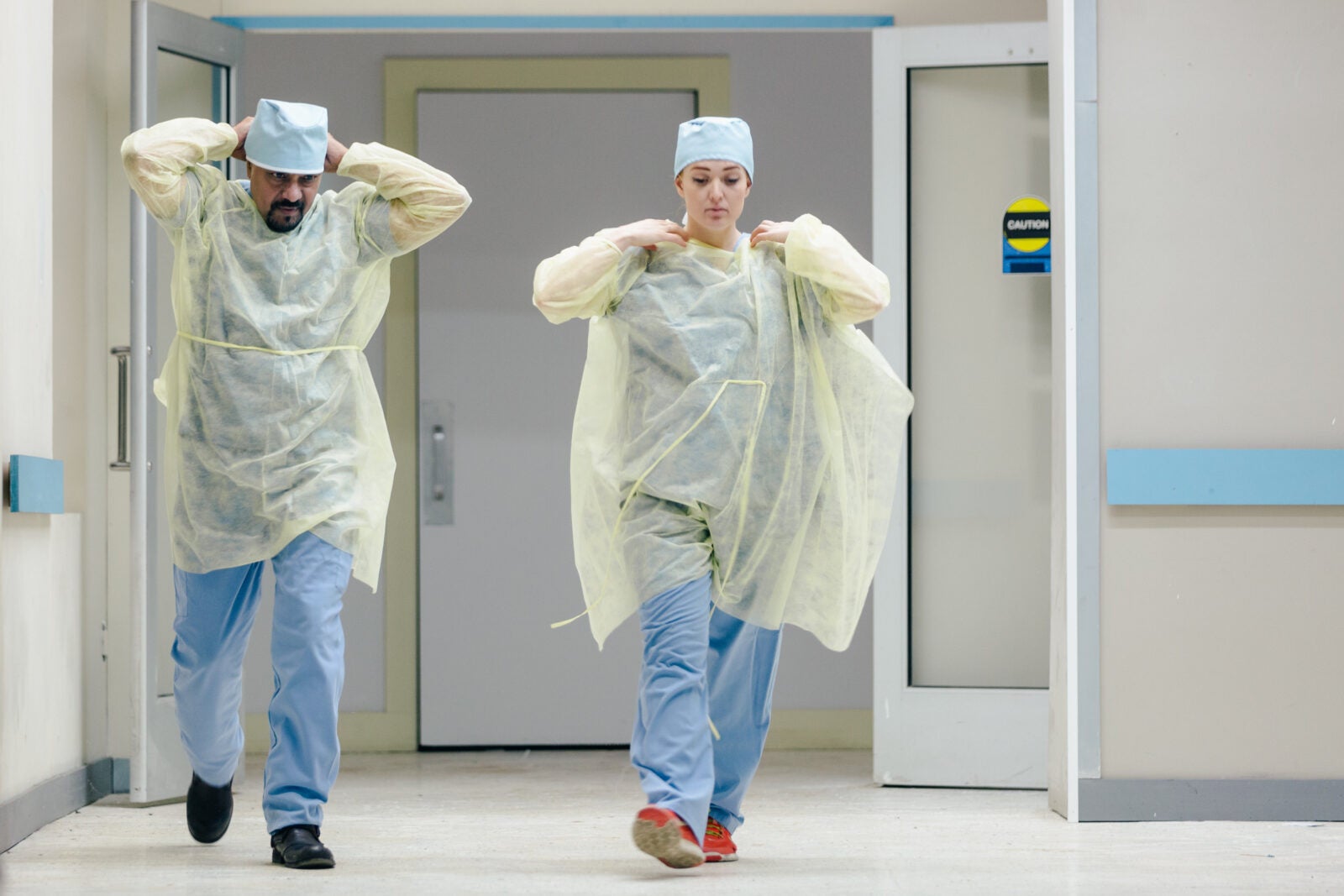 Two medical doctors walking in a hospital hallway in their surgical scrubs.