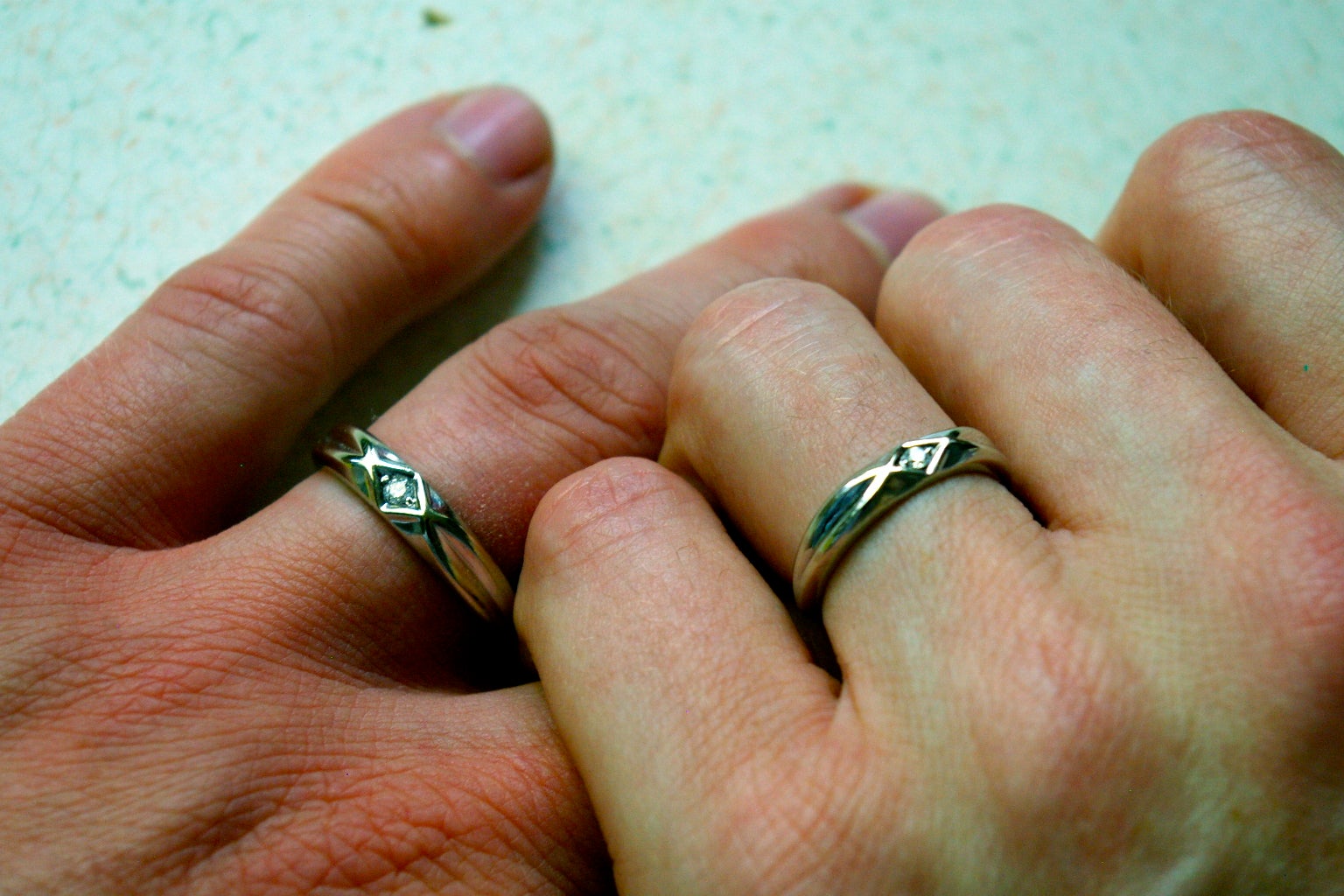 Two hands with matching wedding rings holding each other.
