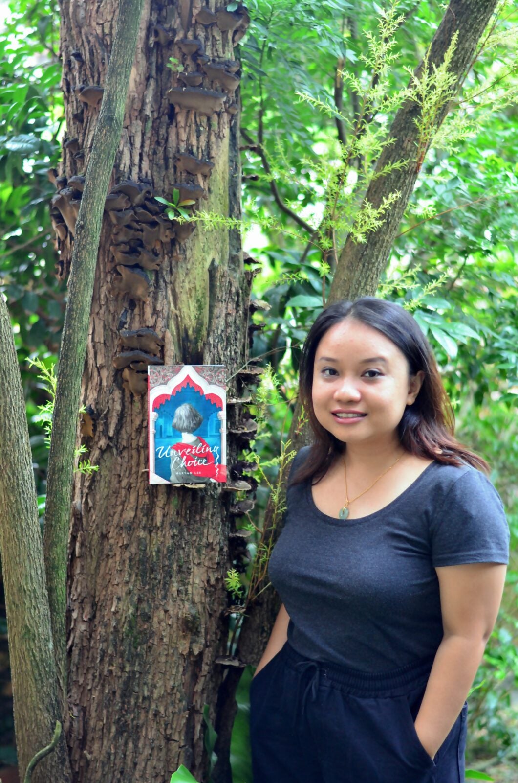 Maryam Lee, activist and feminist, posing with her published book, "Unveiling Choice" (2019)