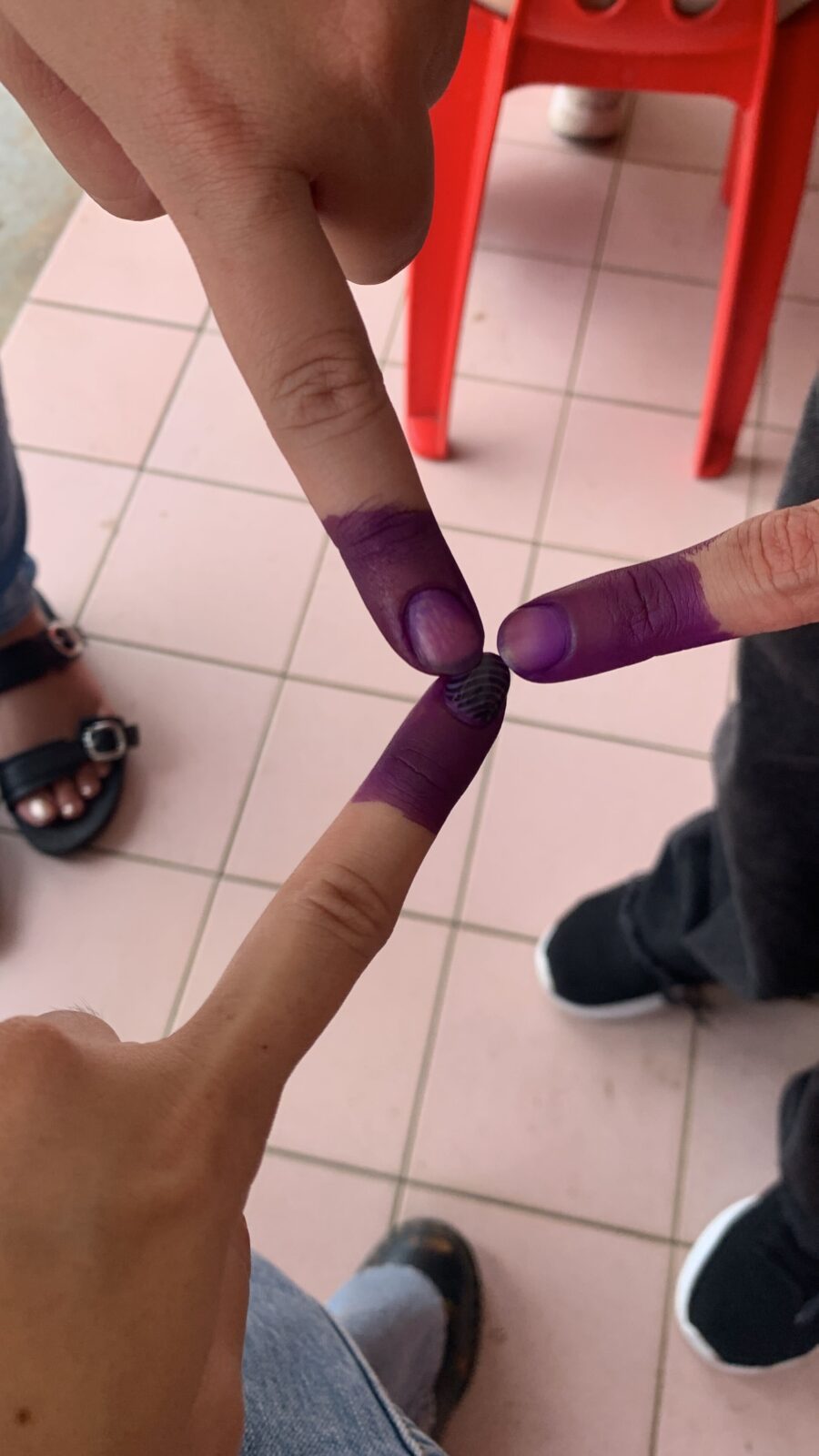 Three hands pointing their painted fingers in the middle to signal that they have voted in Malaysia's General Election of 2022