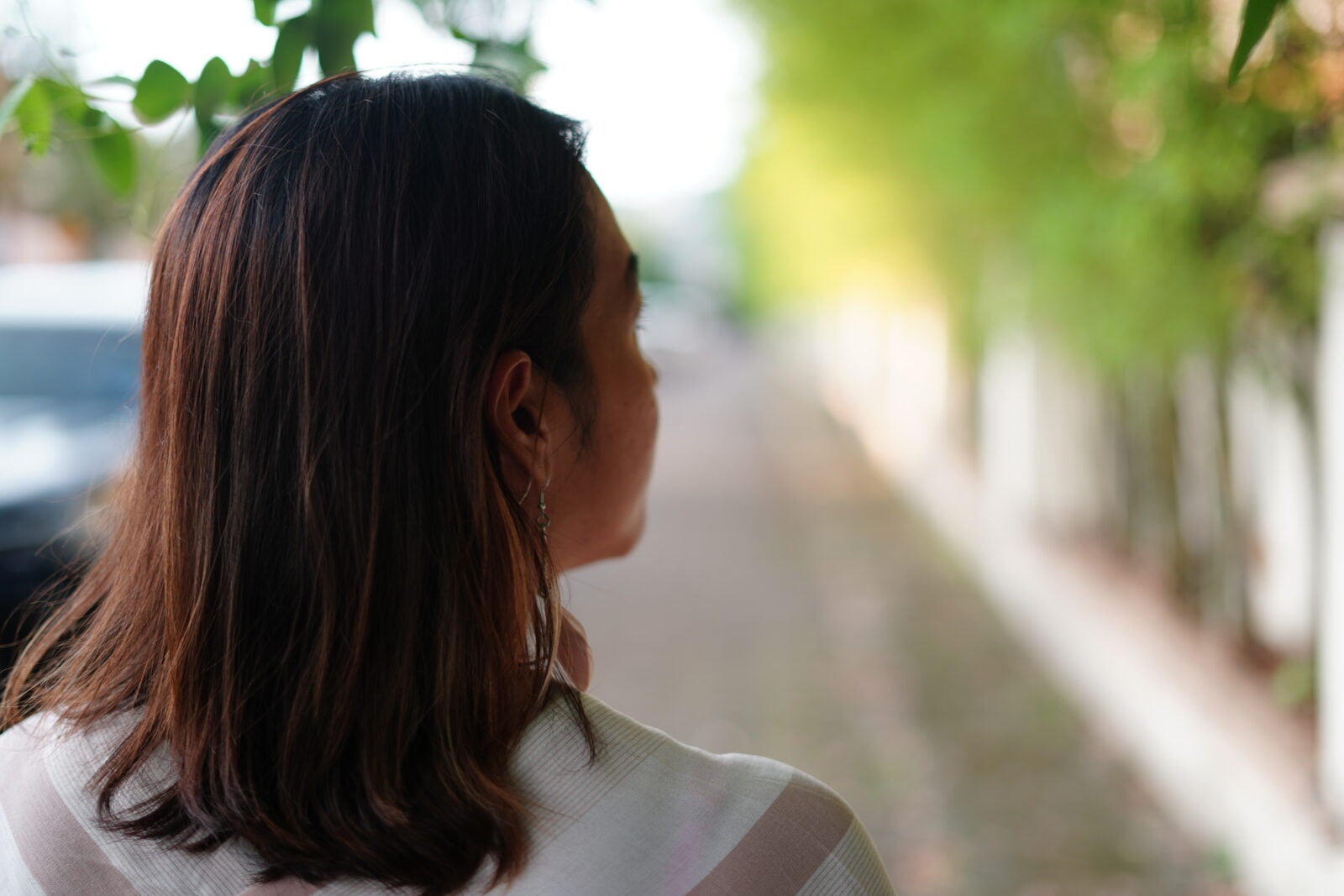 Medium close up of a woman with brown hair looking to her side with the background blurred.