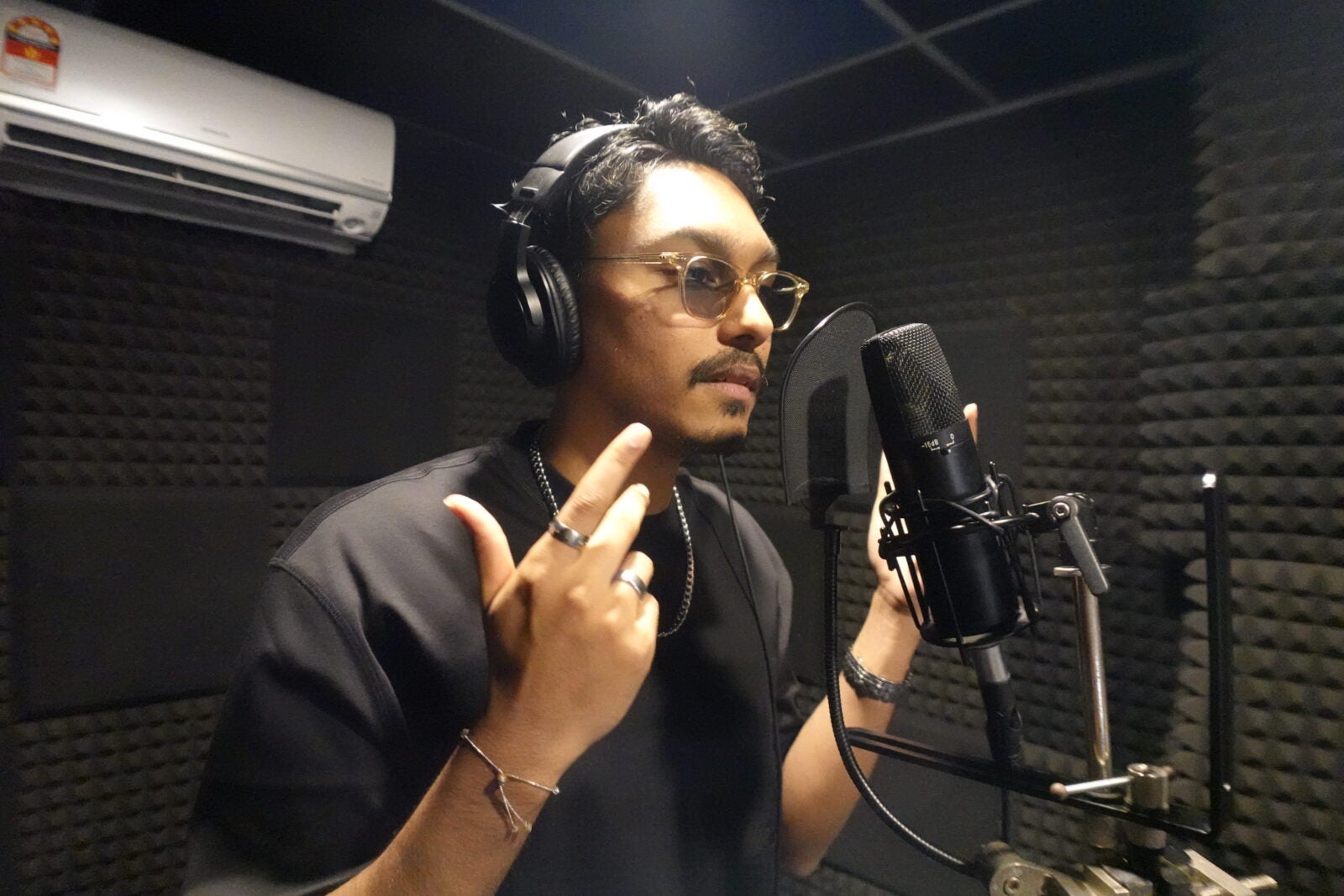 Alan Durairaj, A Malaysian Indian Musician standing infront of a microphone setup in a studio. 