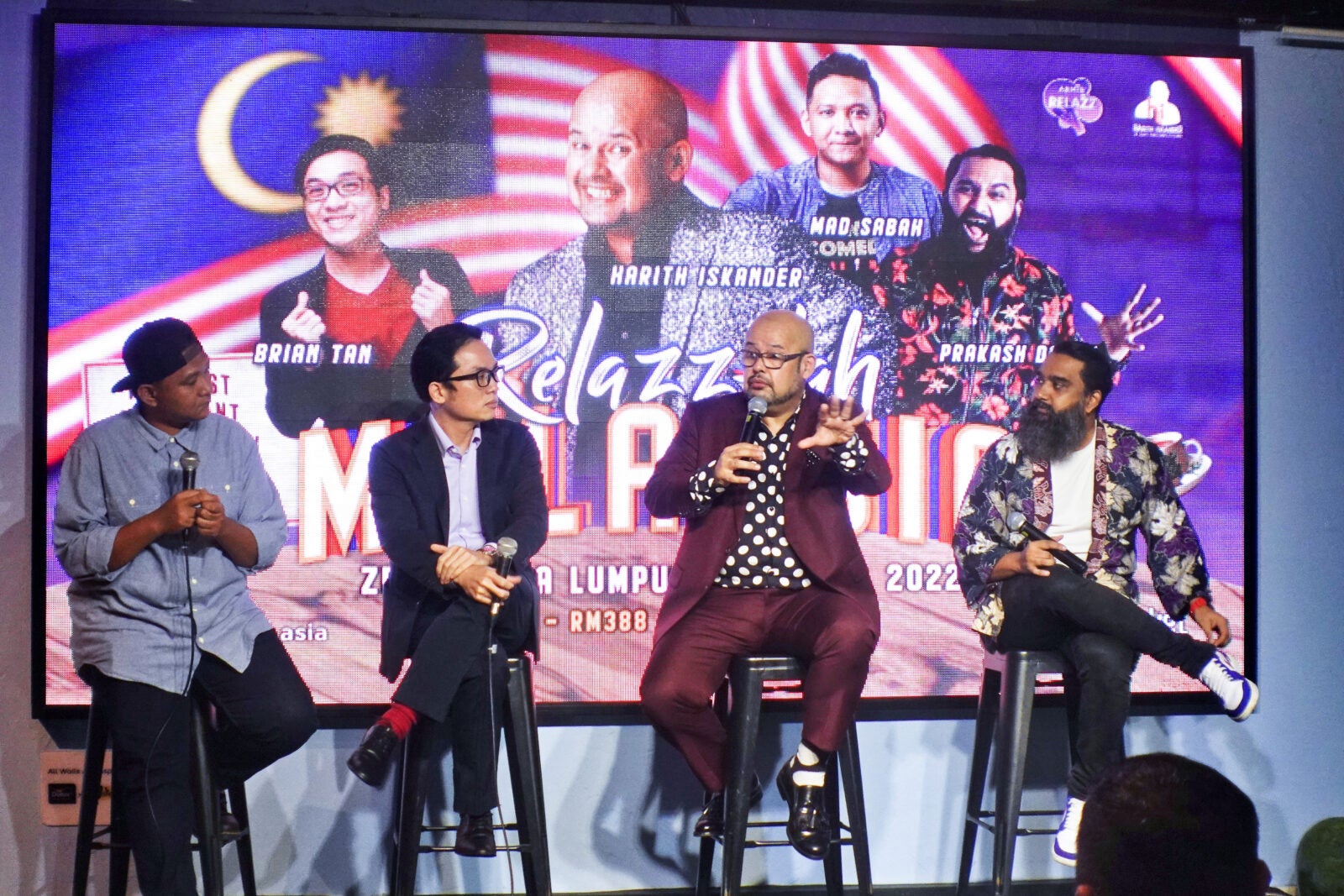 Four Men Sit On A Stool On Stage In Front Of A Screen With Their Faces On It For An Upcoming Event Called &Quot;Relazz-Lah Malaysia&Quot;. They Are Each Holding A Microphone.