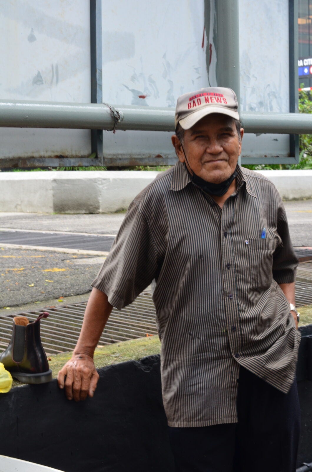 A shoe cobbler wearing a cap and standing at the WISMA MCA, Kuala Lumpur.