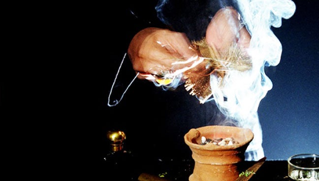Close up of a hand burning some sage and incense.