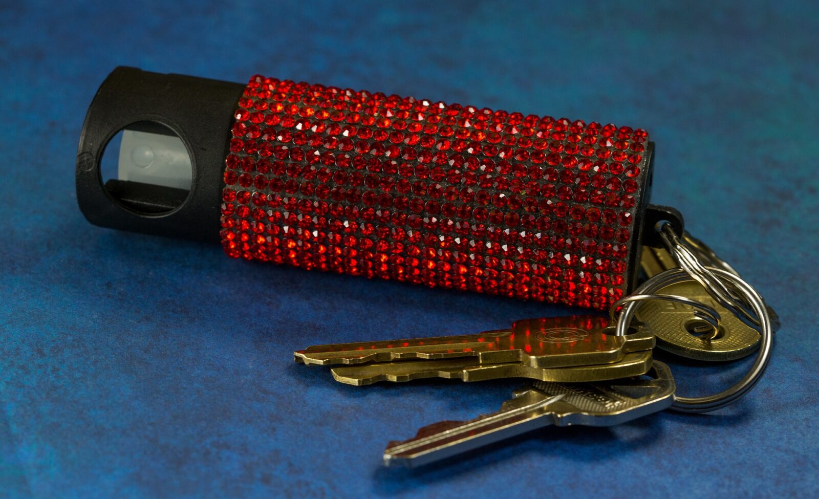A pepper spray that has been bedazzled with red jewels and hooked as a keychain.