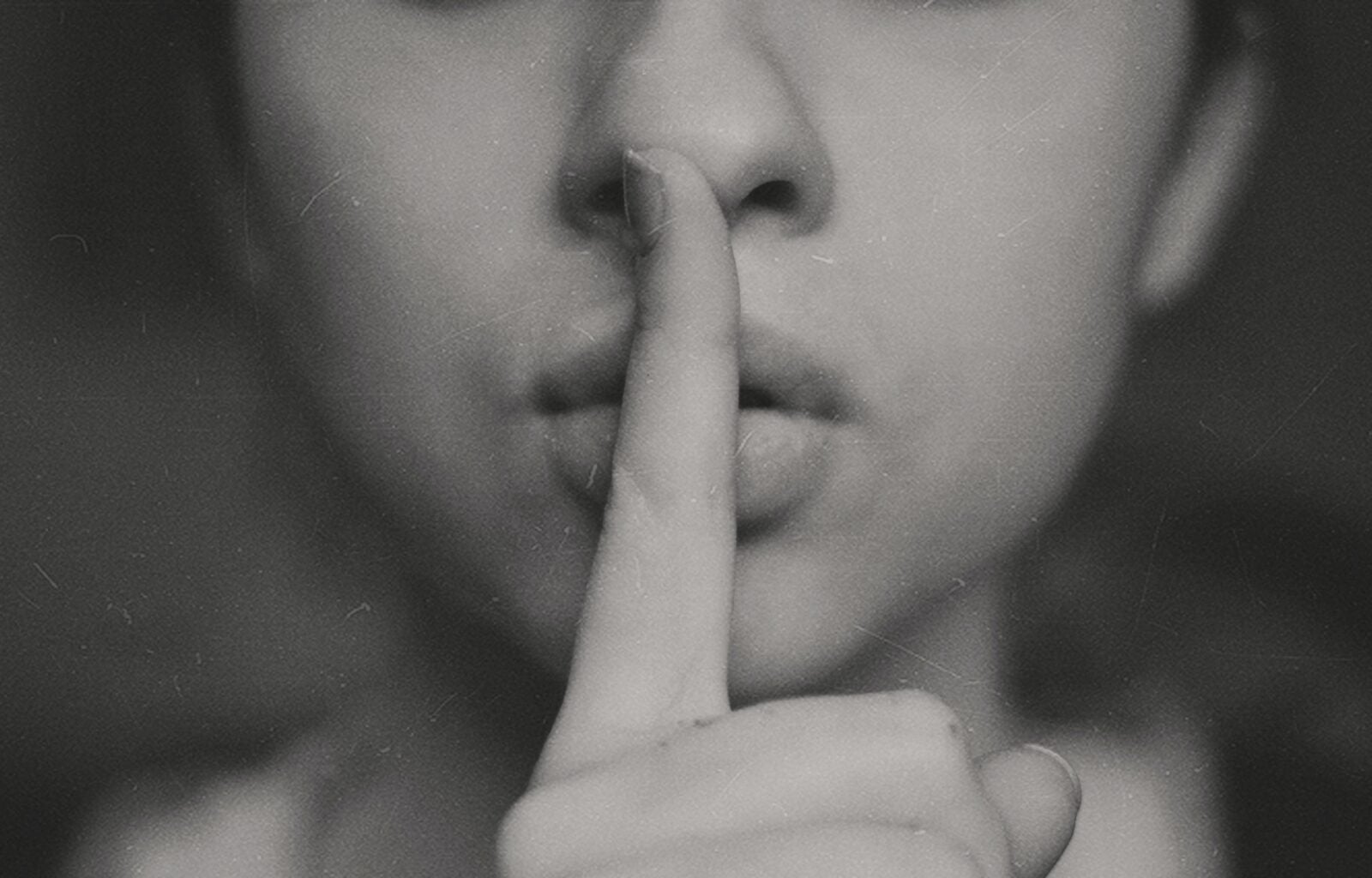 A woman with her fingers to her lips in a shushing motion.