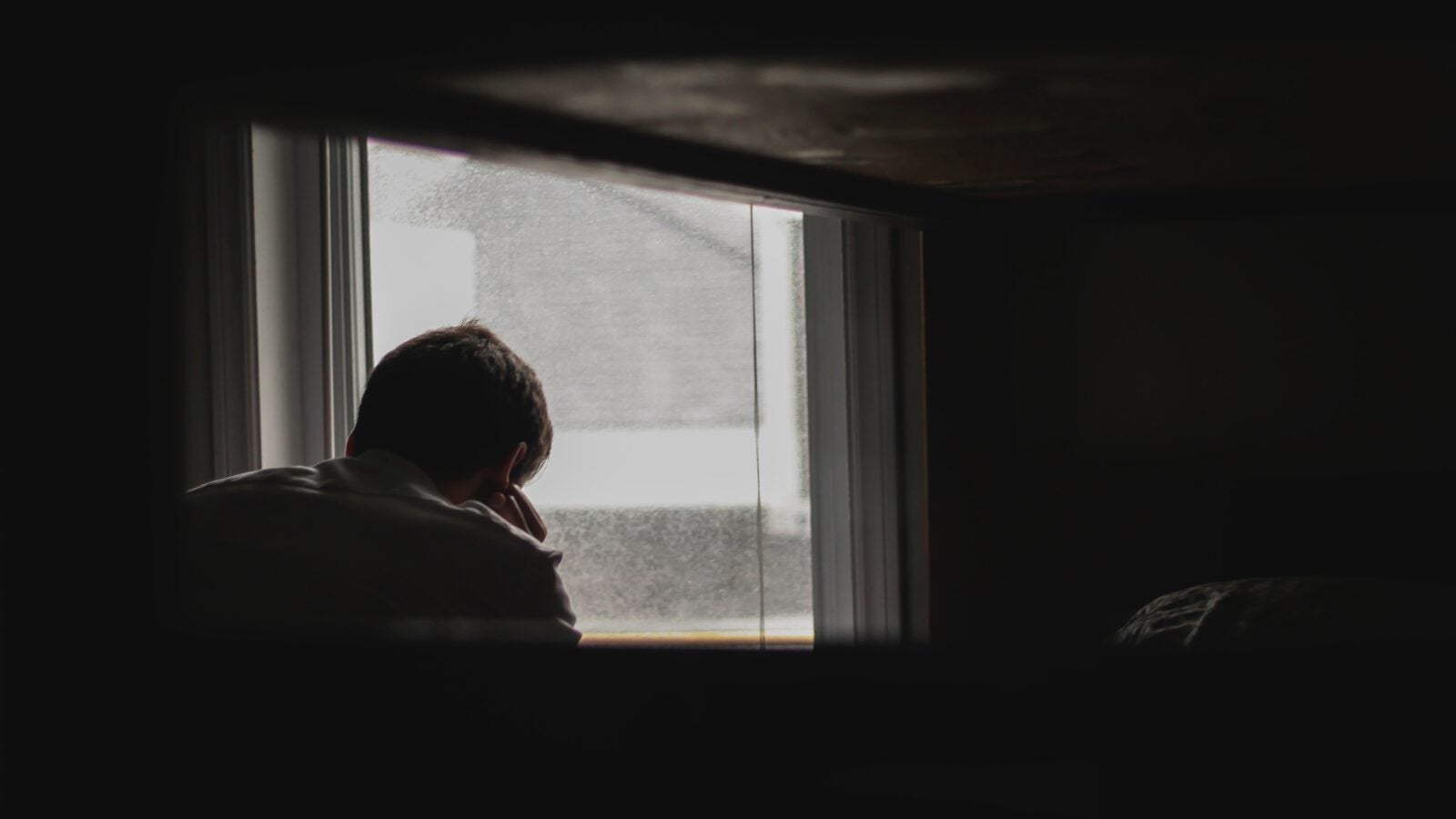Silhoutte of a man sitting in front of a window.