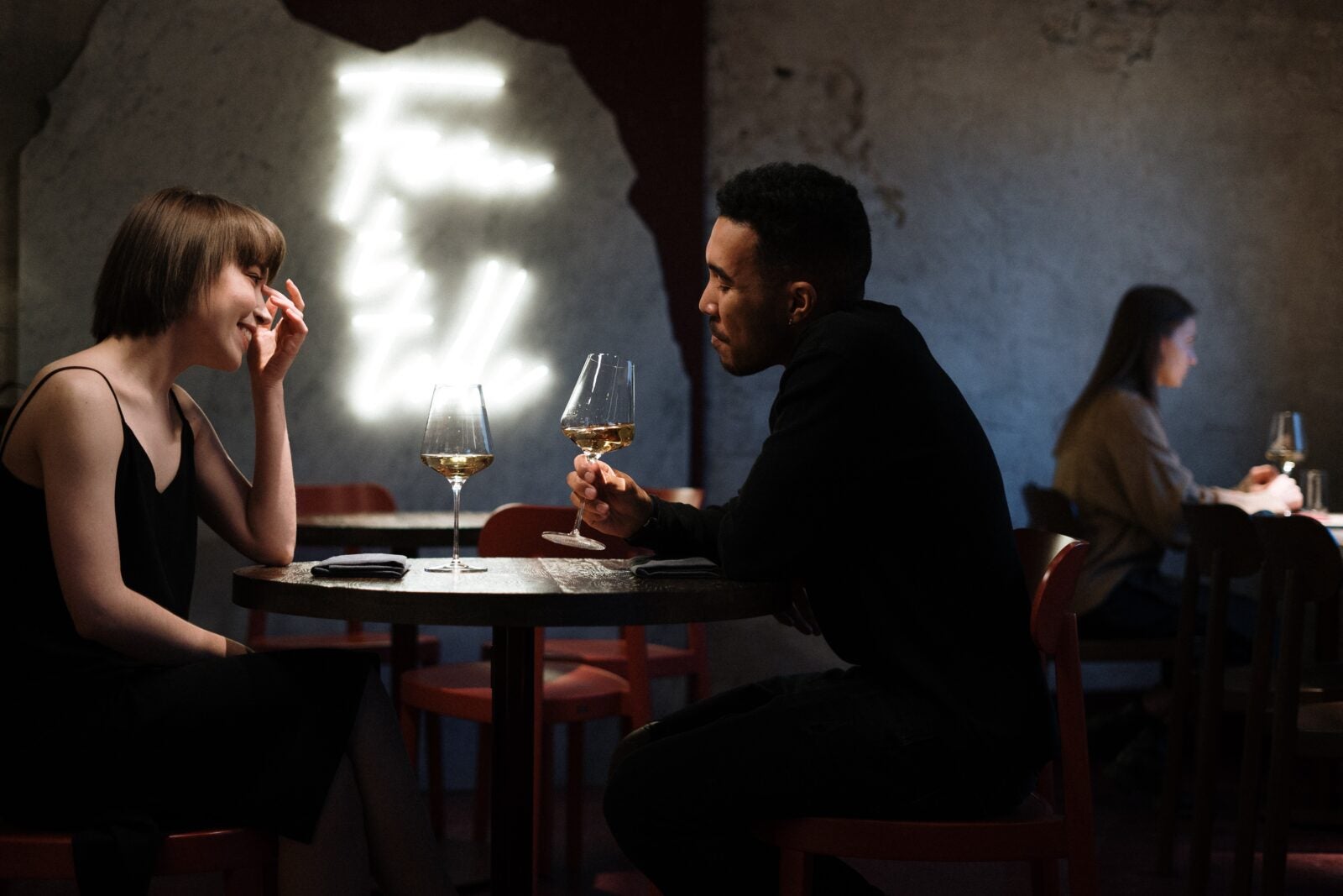 A couple on a date in a dark cafe with light decorations on the wall.