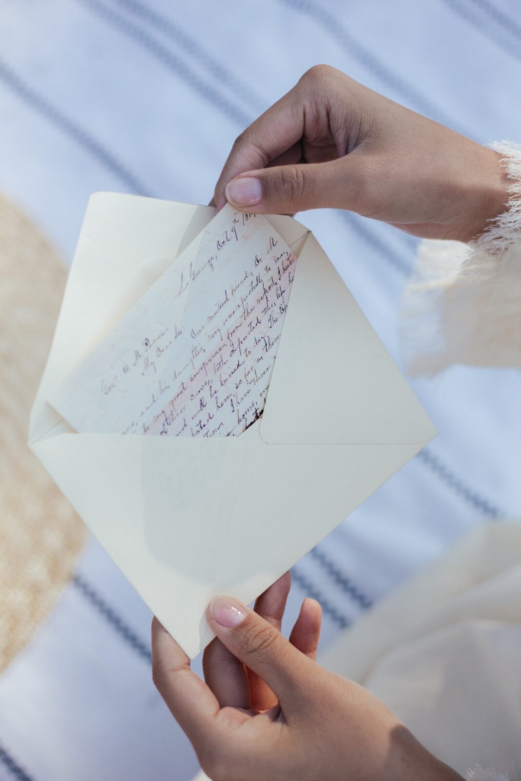 A woman's hand taking out a handwritten note from an envelope.