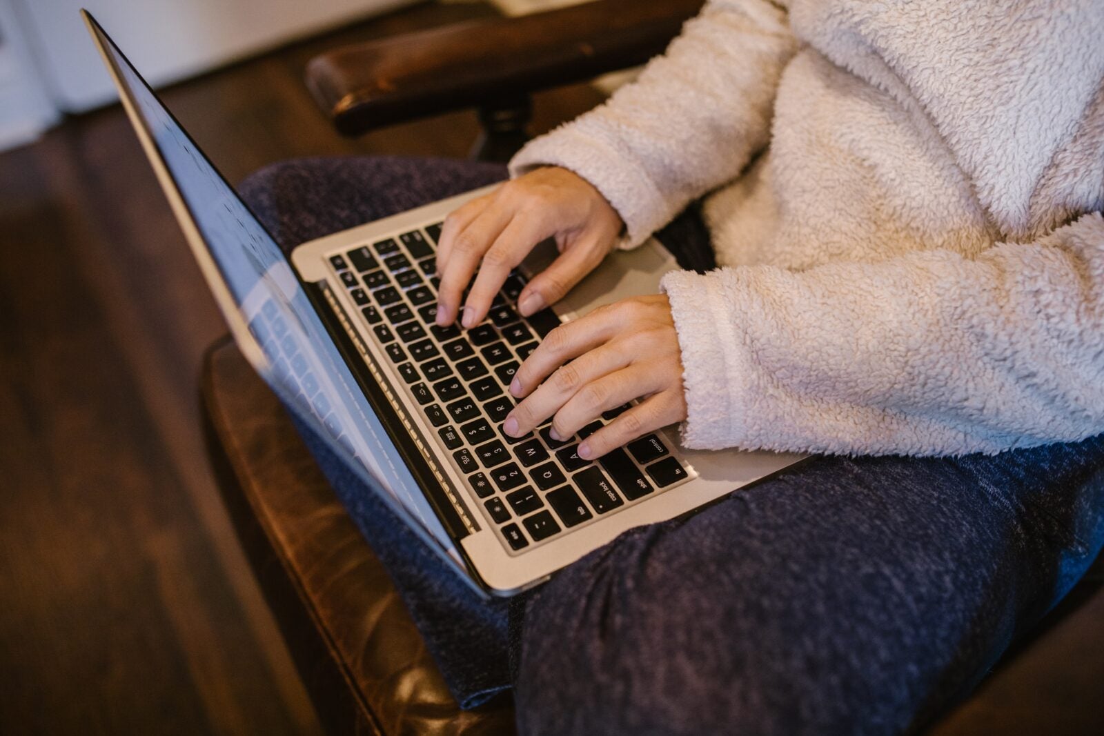 Man wearing long sleeved sweater using the laptop