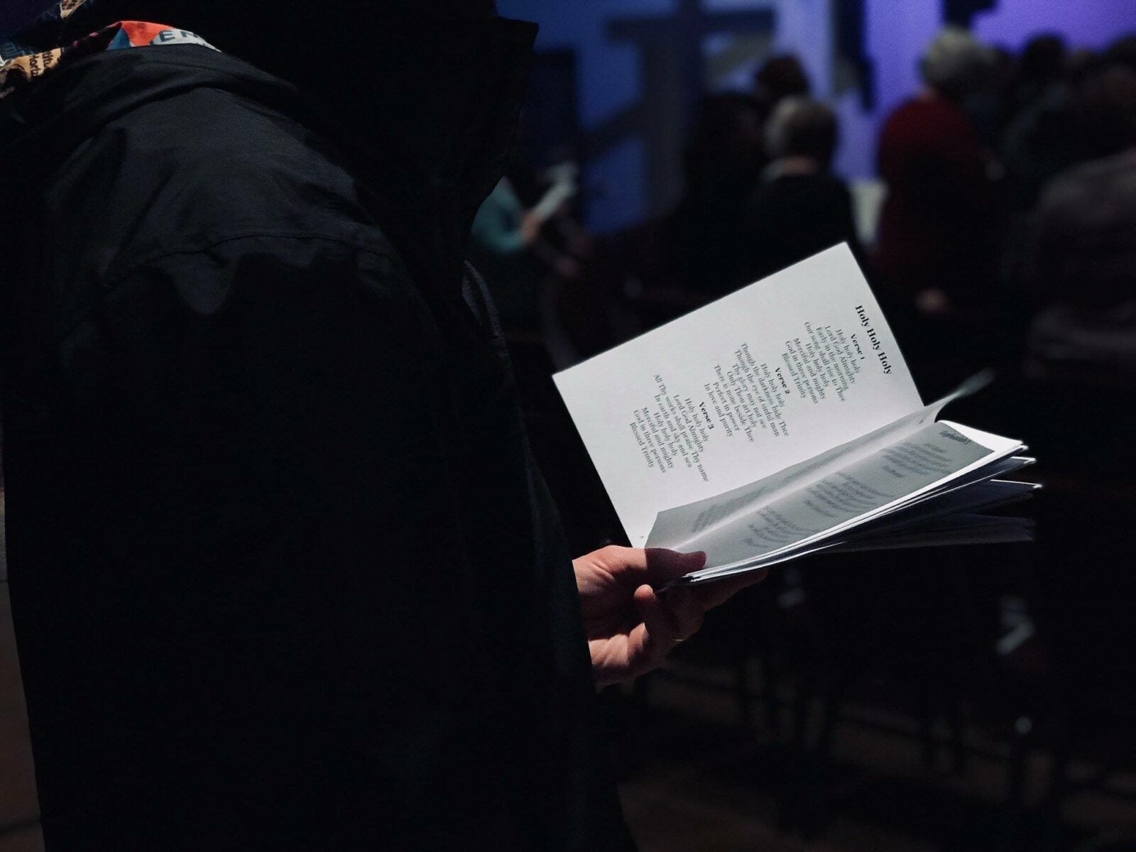 Man holding onto a paper with lyrics written on them at a church.