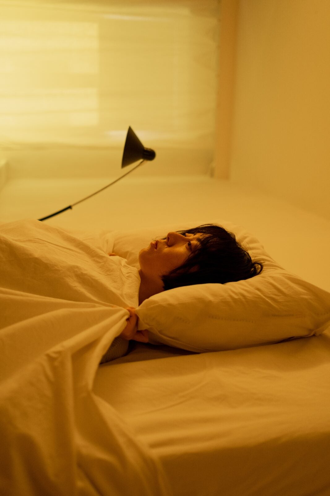 A young Asian woman with short hair laying on a bed.