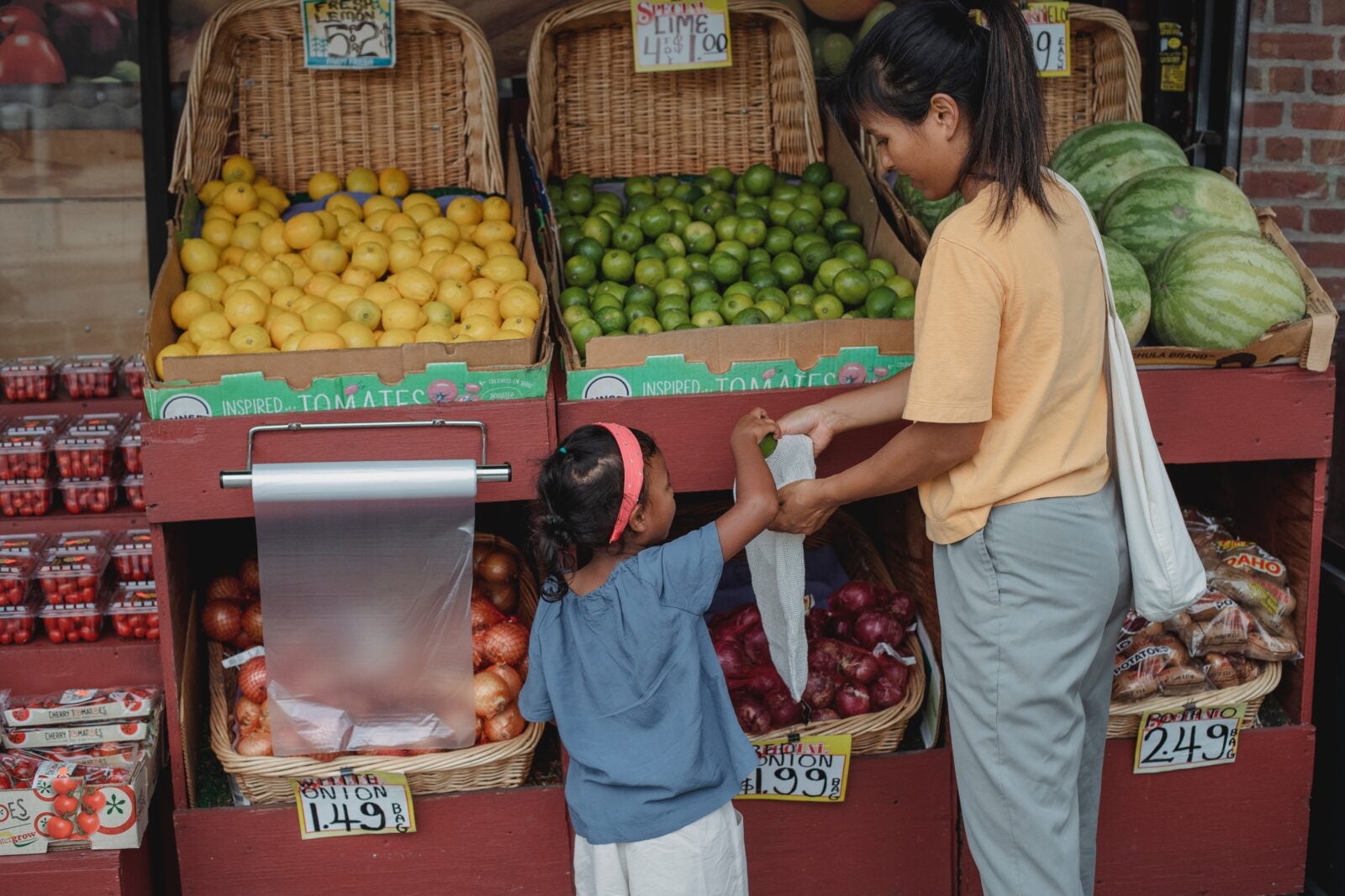 Ethnic customer choosing fruits with daughter at market