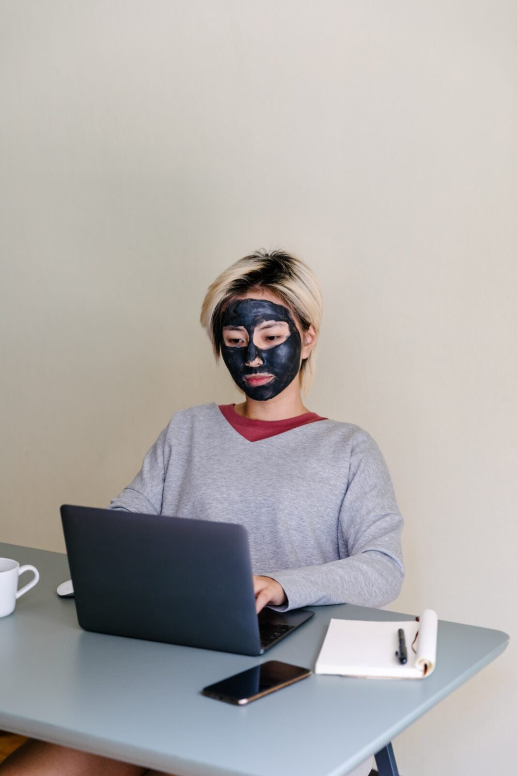 Asian woman wearing a black facial mask while using her laptop.