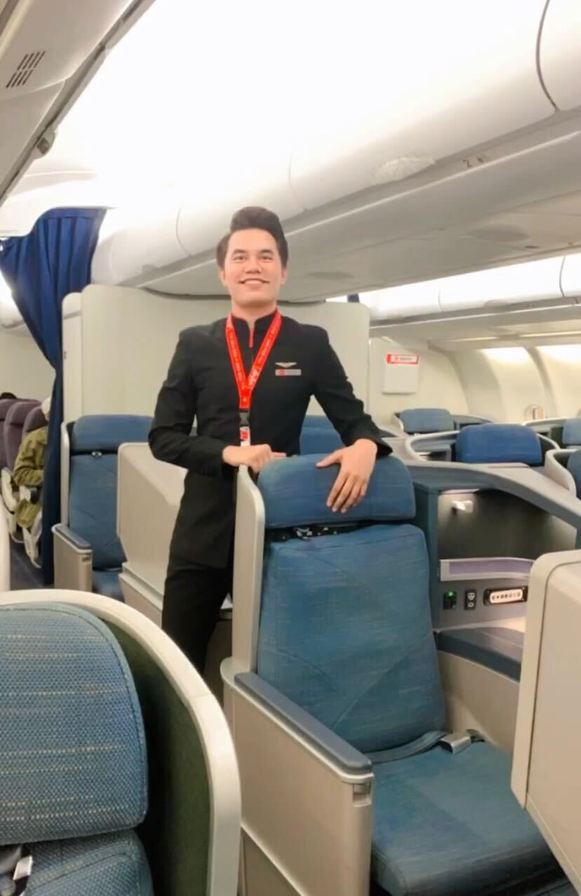 Erween poses smiling on the plane. He is wearing his flight crew uniform.