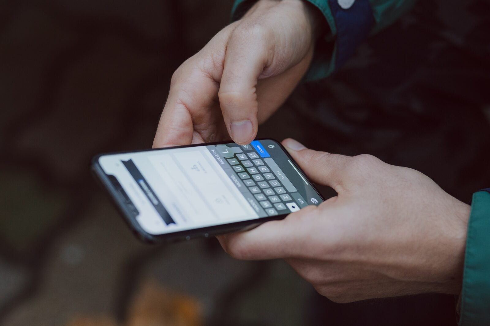 Close up image of a man's hands as he types on his phone. The phone has a messenger app opened.