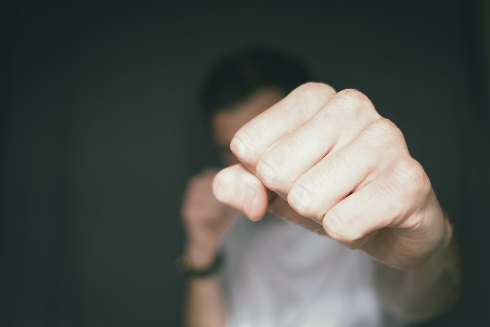 Image shows a man with his fist outstretched towards the camera. Only his fists are focused while the man and his background are blurred.