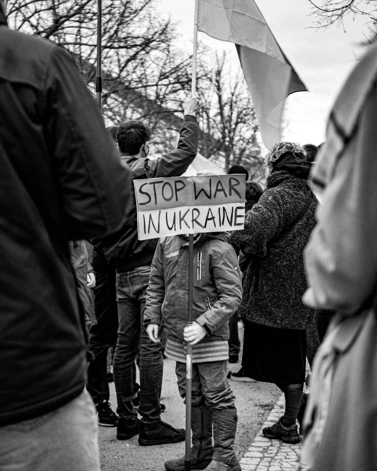 Black and white of a child holding a sign that reads: Stop War In Ukraine. 