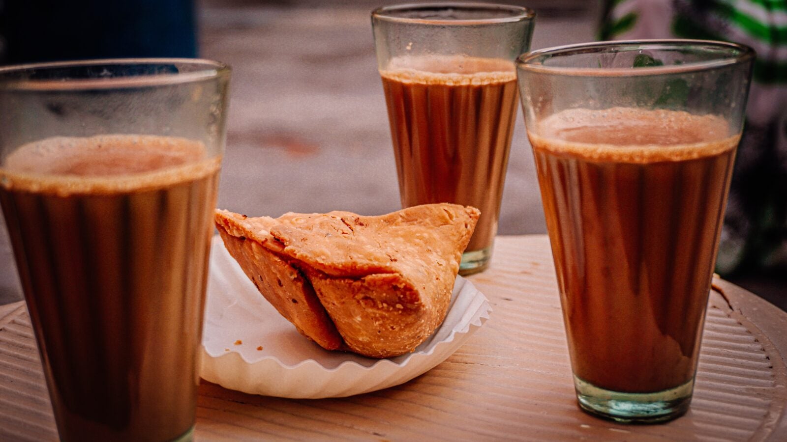 Image shows three full glasses of coffee around a single serving of currypuffs.