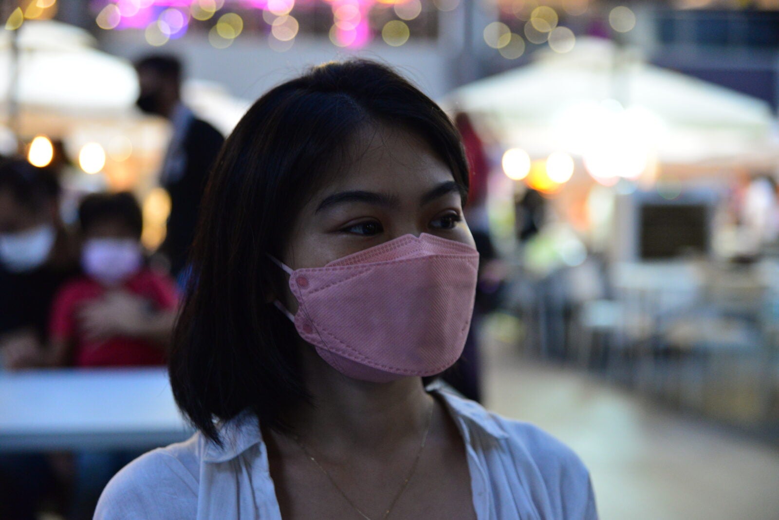 The Narrator Looks Away From The Camera, Still Wearing Her Mask. 